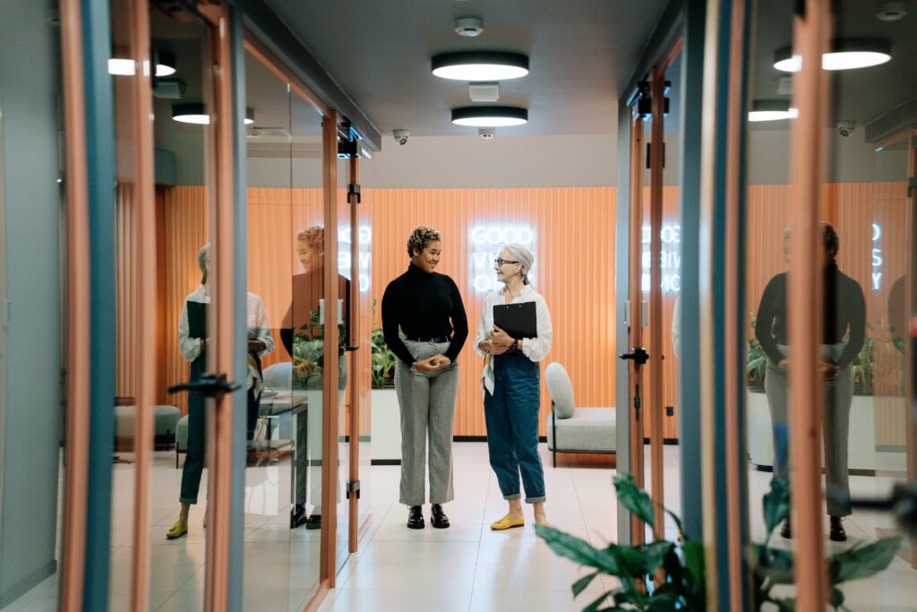 two women standing in an office hallway looking at each other
